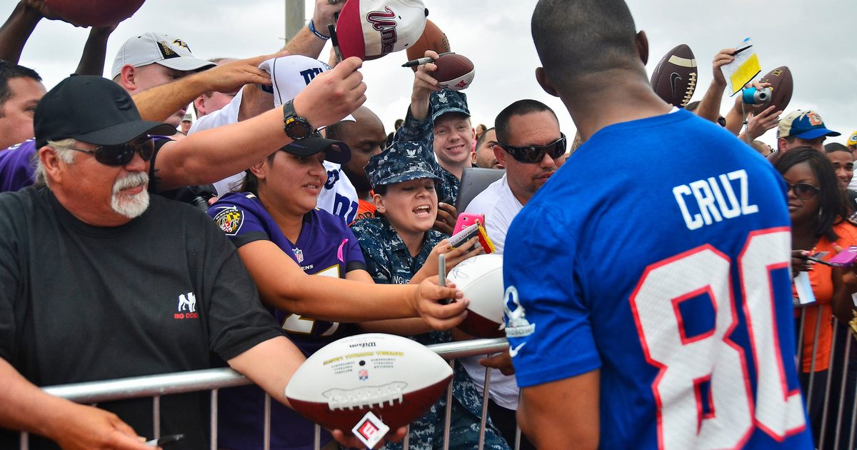 Victor Cruz, foreground, wide receiver with the New York Giants, signs autographs for U.S.