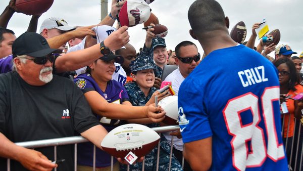 Victor Cruz, foreground, wide receiver with the New York Giants, signs autographs for U.S.